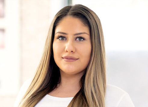 Junge Frau mit langen, glatten Haaren lächelt freundlich in einem modernen Büro.